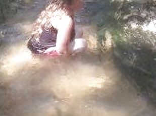 Cute long hair girl on her knees looking for shells to collect in popular spring creek part 2