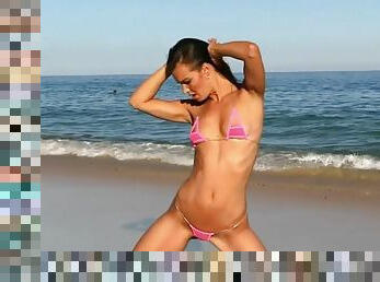 Brunette bikini models poses on the beach