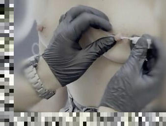 Sexy wife piercing her nipples in a piercing studio. Close up.